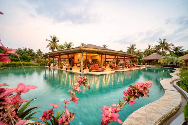 The big pool and the restaurant pavilion in the middle of the water, pink flowers in the foreground