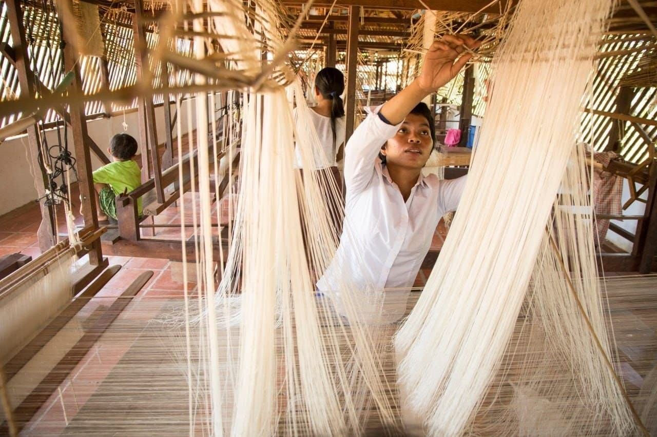 Weaver setting up the silk threads on a loom