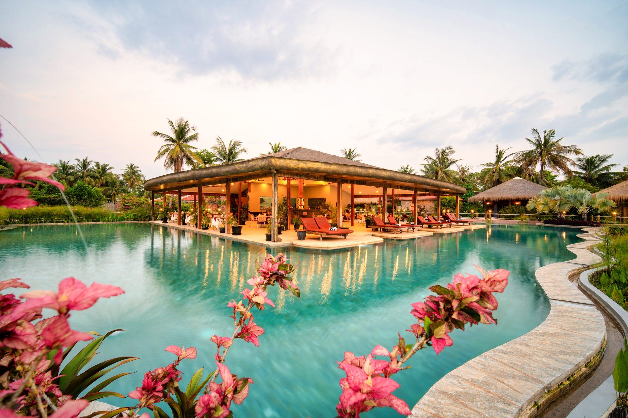 The big pool and the restaurant pavilion in the middle of the water, pink flowers in the foreground