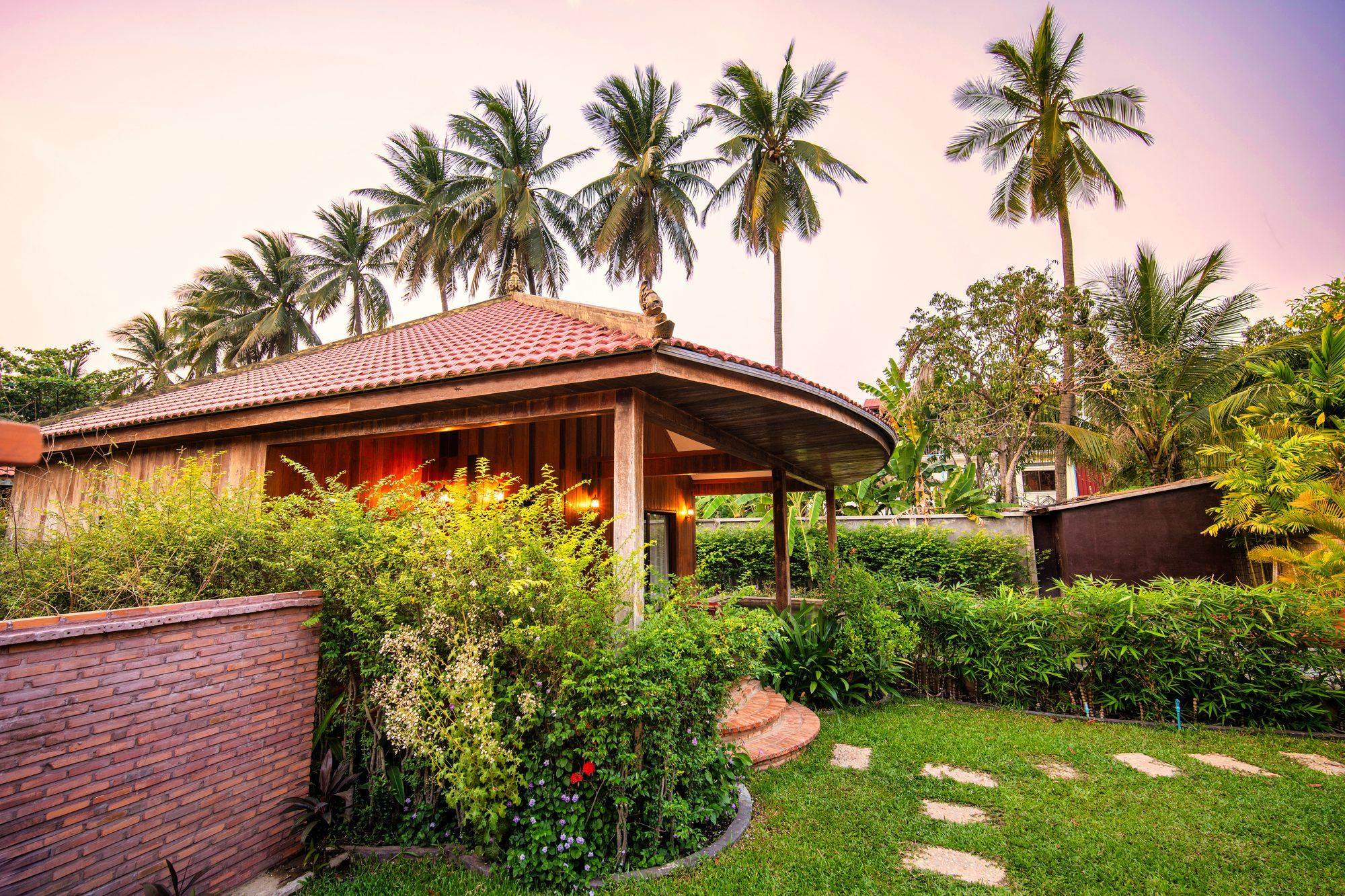 A tiled-roof villa in a garden of palms